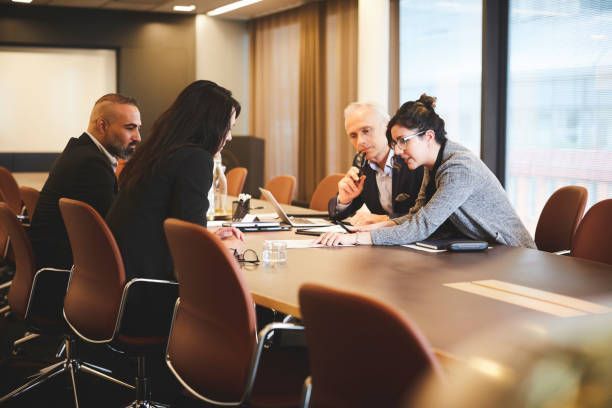 A group of people are sitting around a conference table in a conference room.