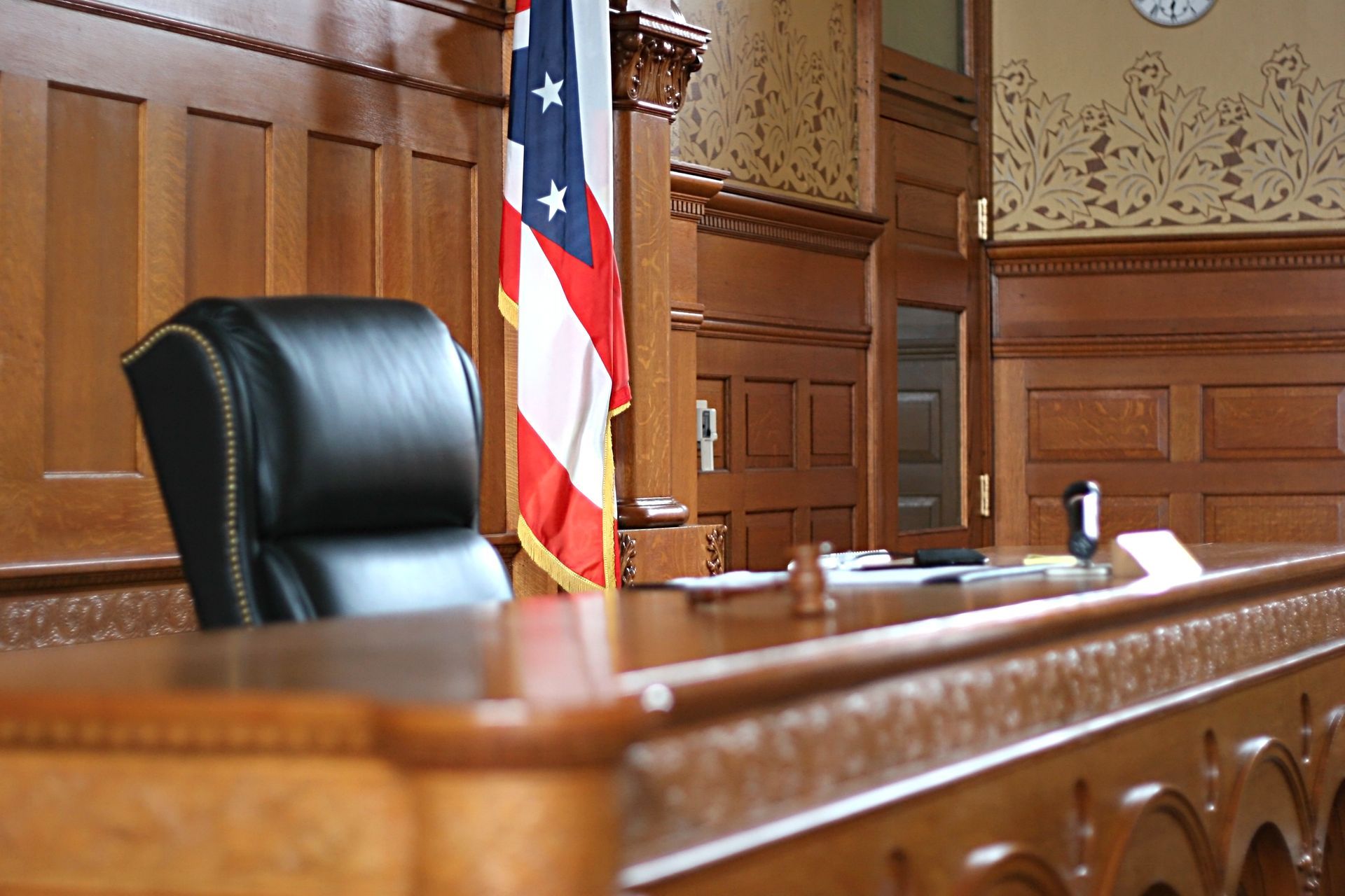 A judge 's bench in a courtroom with an american flag hanging on the wall.