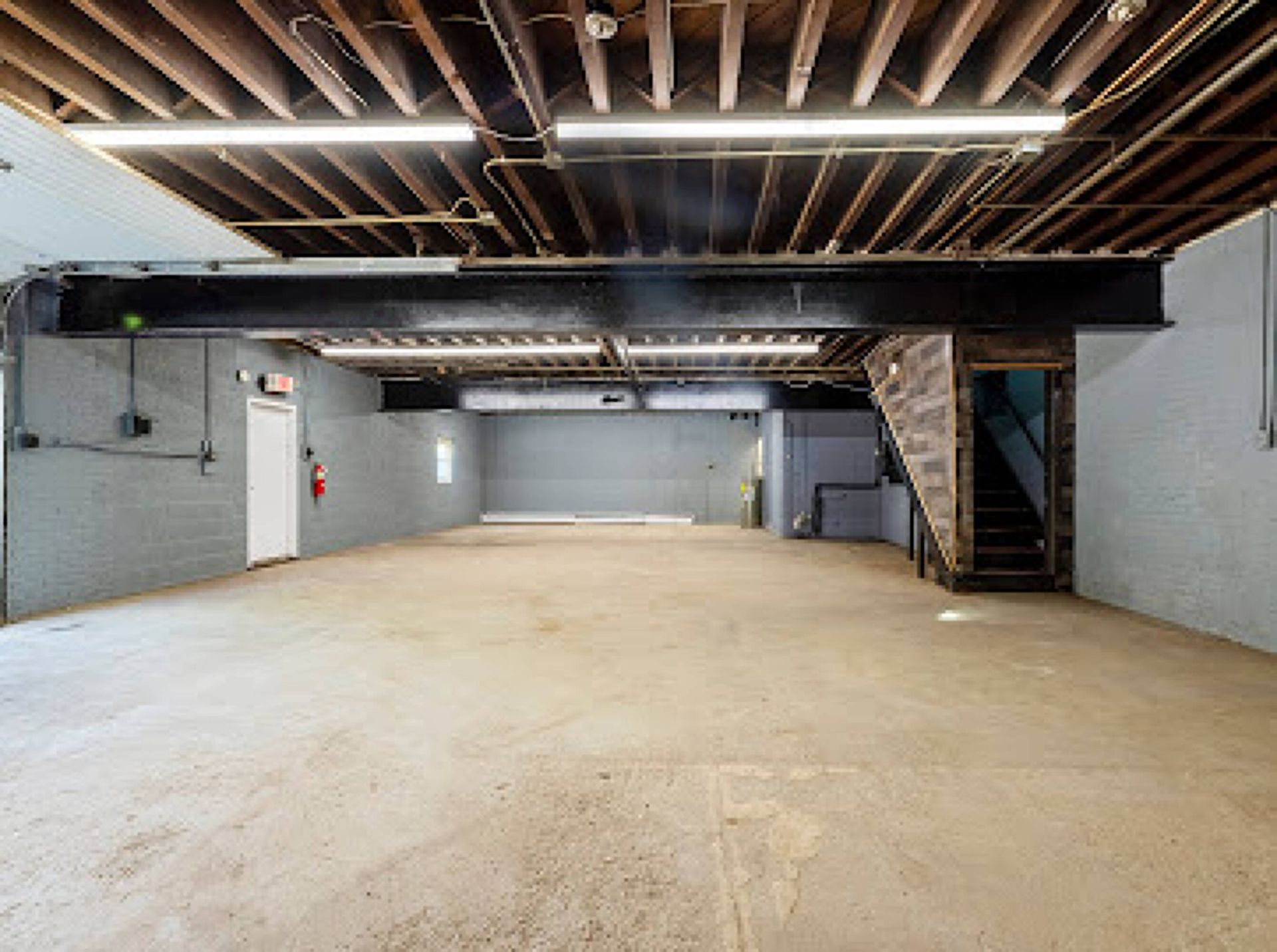 A large empty room with a staircase leading to the second floor.