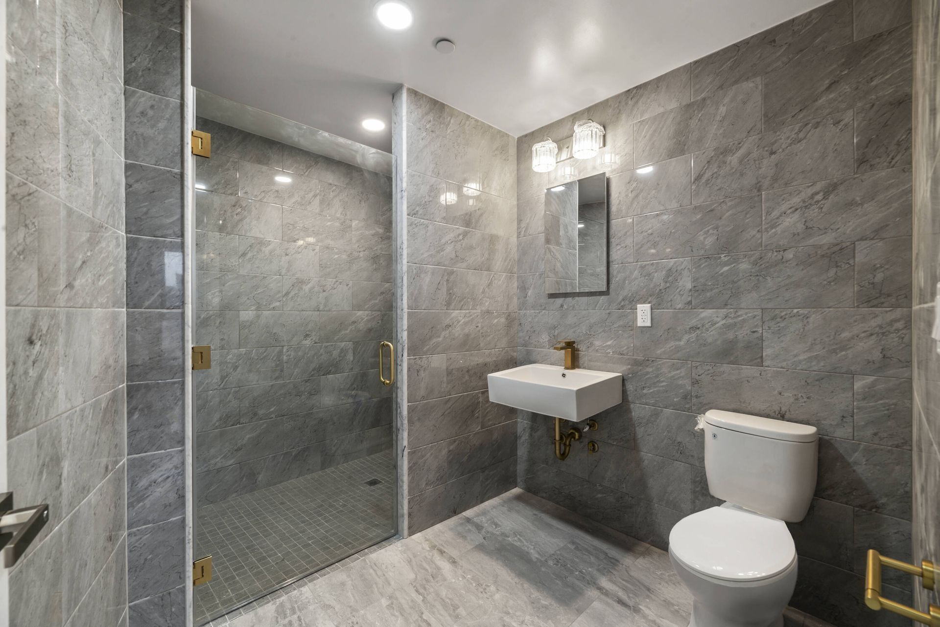 A bathroom with a toilet , sink and walk in shower.