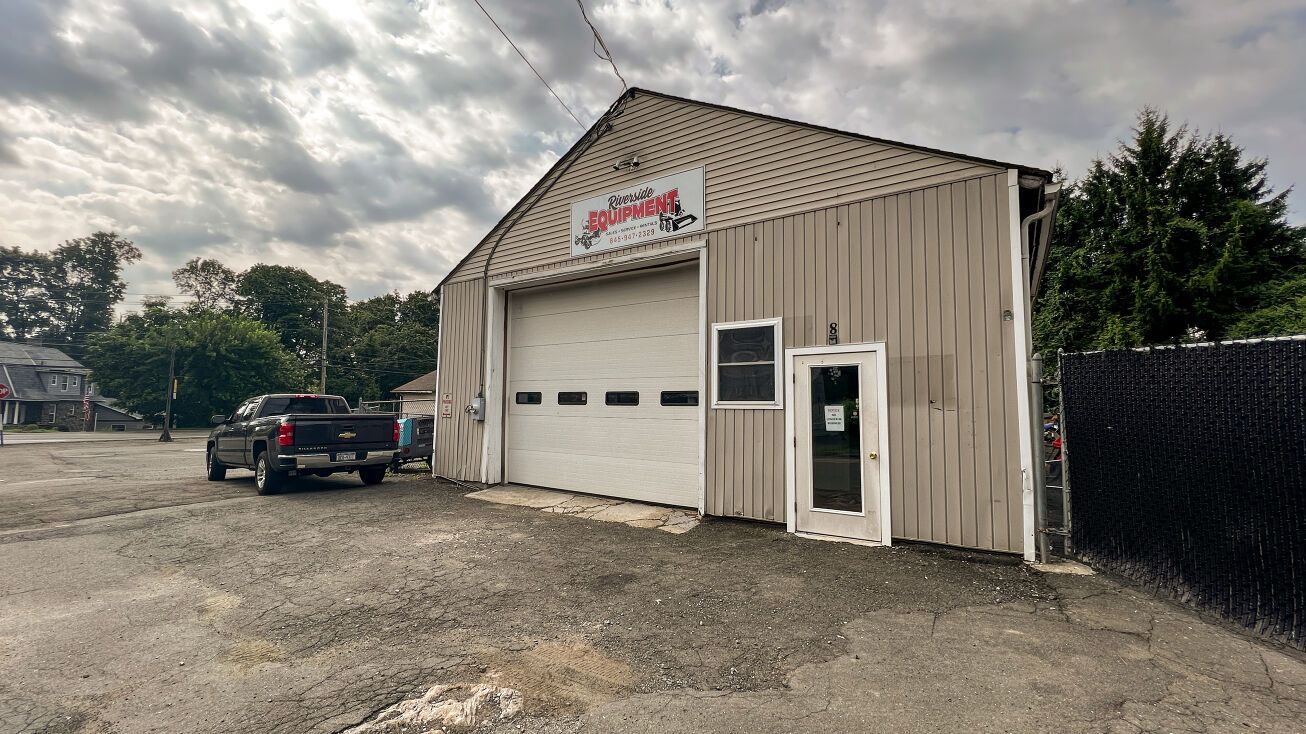 A truck is parked in front of a garage with a large garage door.