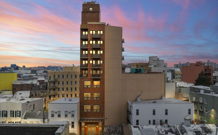 An aerial view of a tall building in a city at sunset.