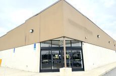 A large white building with a brown roof and black doors.