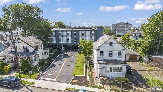 An aerial view of a residential area with houses and cars parked on the side of the road.