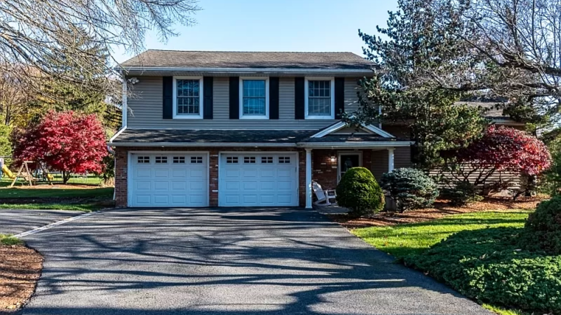 A large house with two garage doors and a driveway