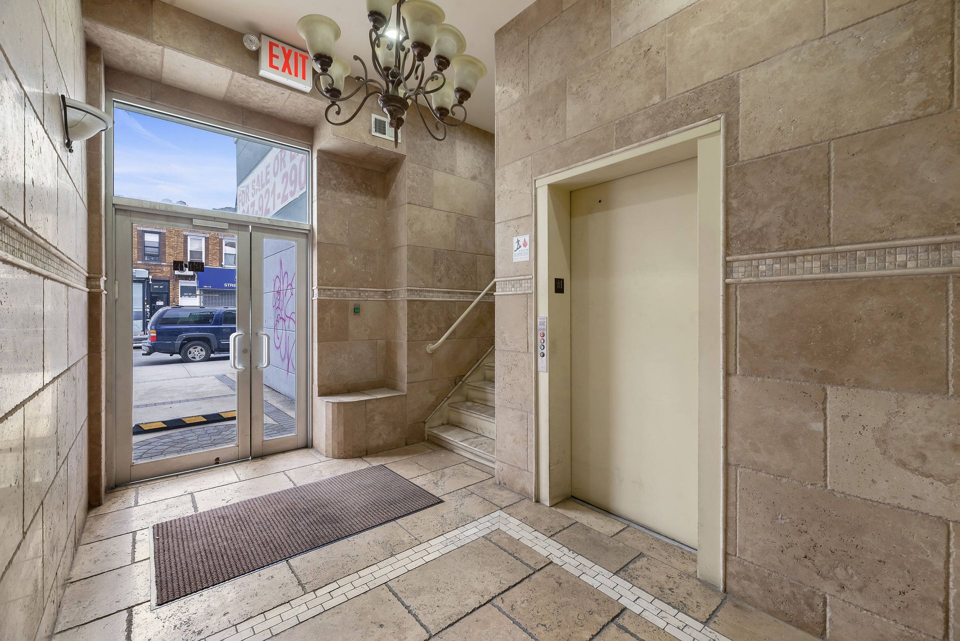 A hallway with a staircase and an elevator in a building.