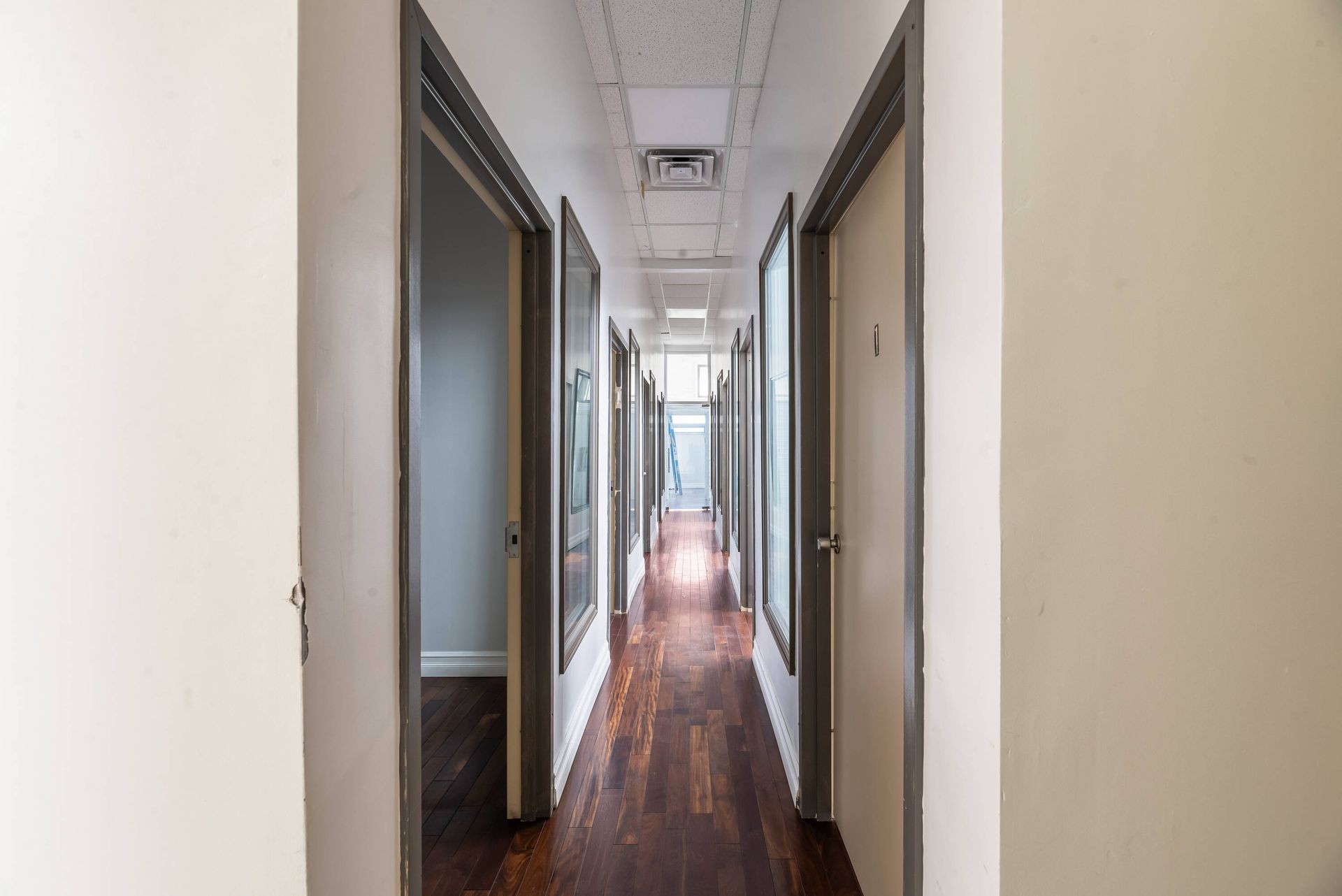 A long hallway with wooden floors and white walls.
