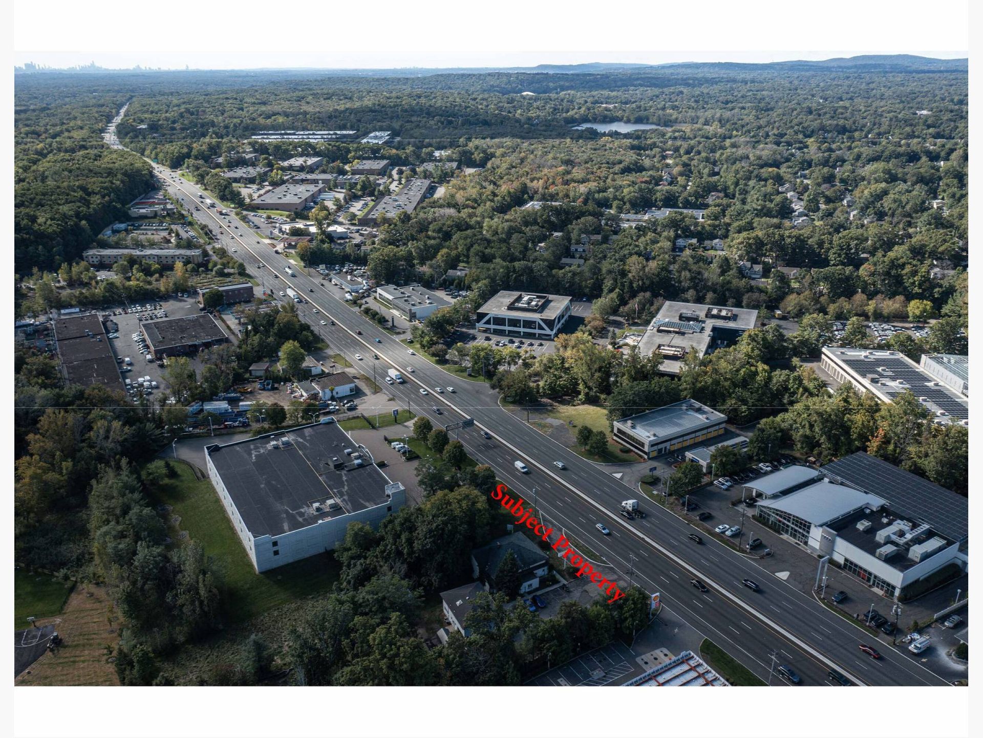 An aerial view of a highway surrounded by trees and buildings.