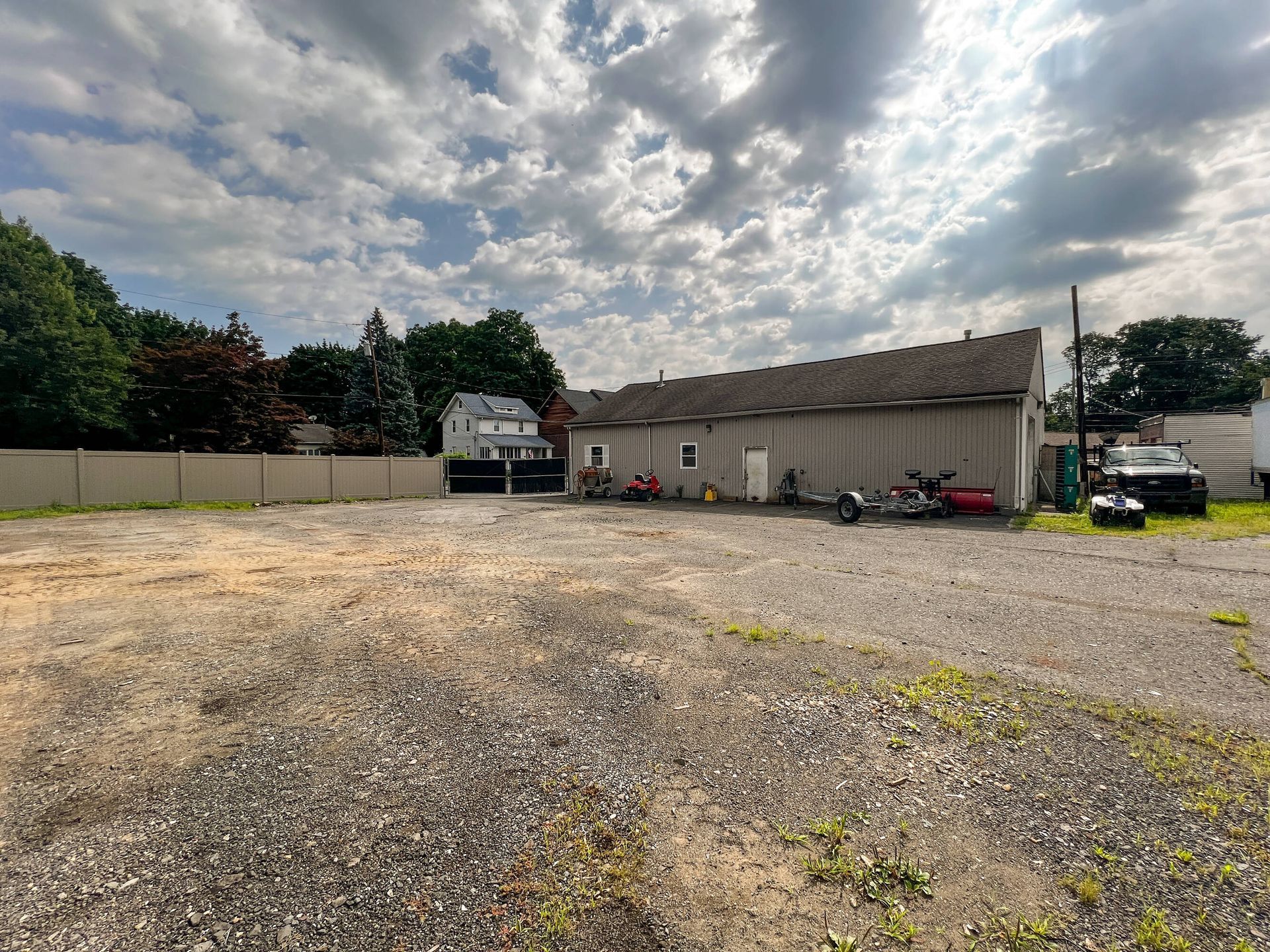 An empty gravel lot with a building in the background
