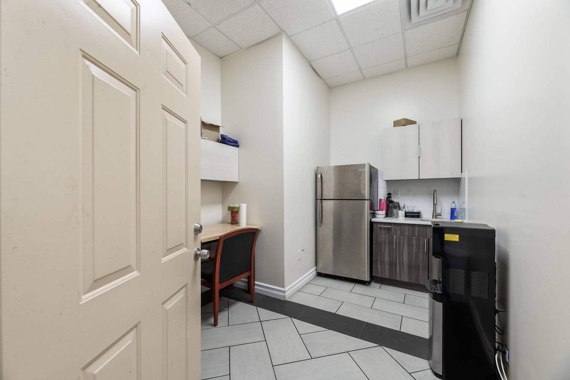 A kitchen with a refrigerator , sink , and desk.