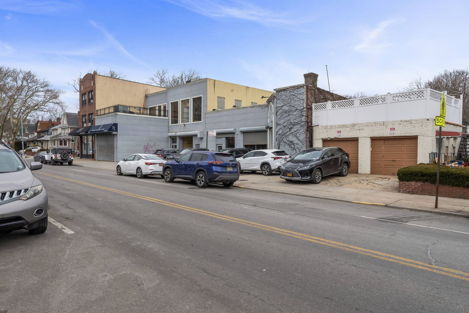 A row of cars are parked on the side of a city street.