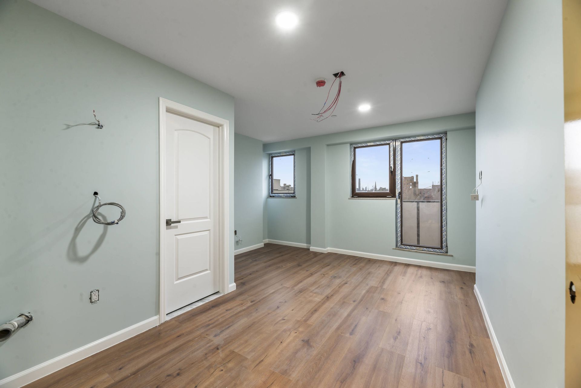 An empty room with hardwood floors and a white door