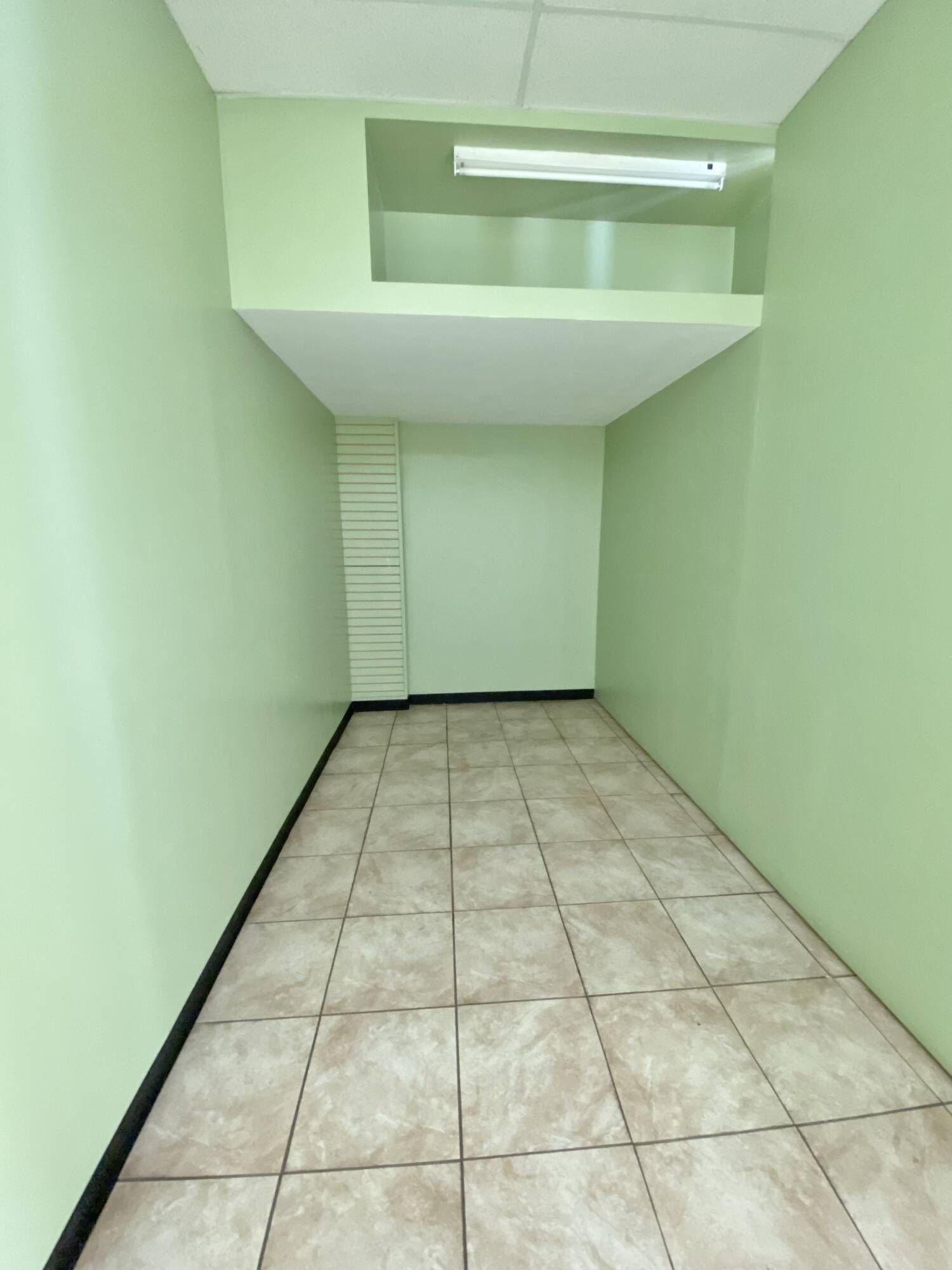 An empty room with a tiled floor and green walls