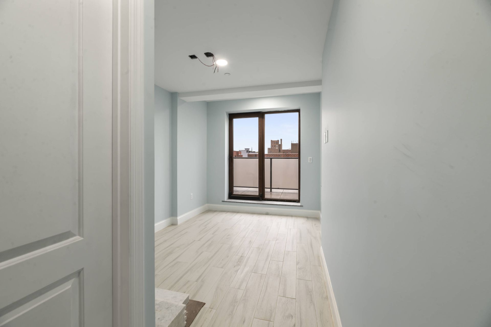 An empty room with a sliding glass door and a balcony.