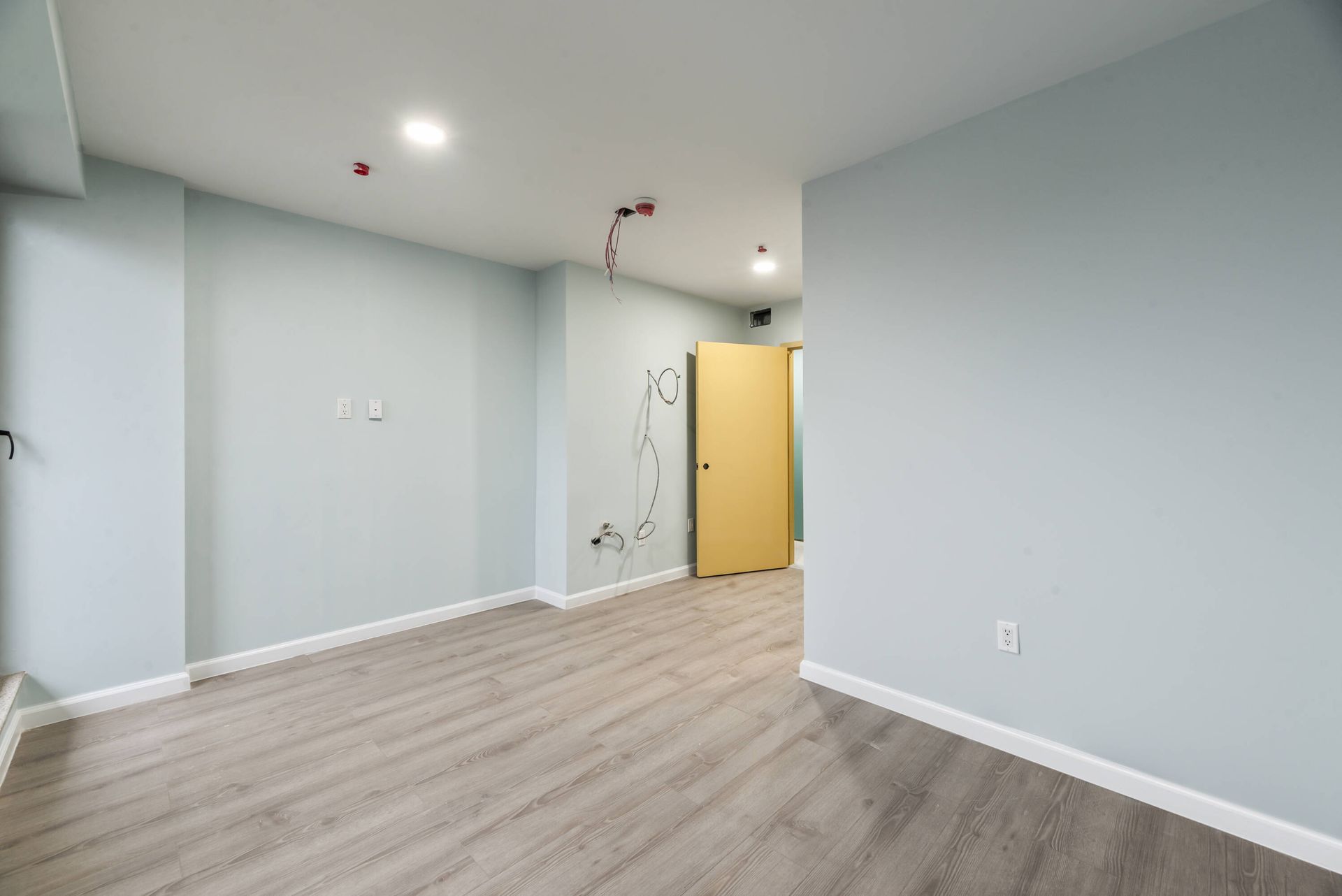 An empty room with a wooden floor and a yellow door.