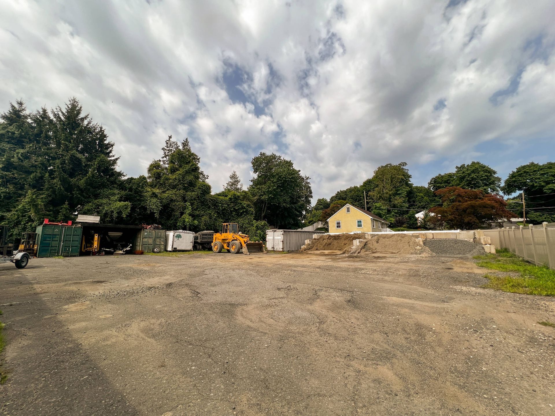 A large empty lot with a yellow house in the background.