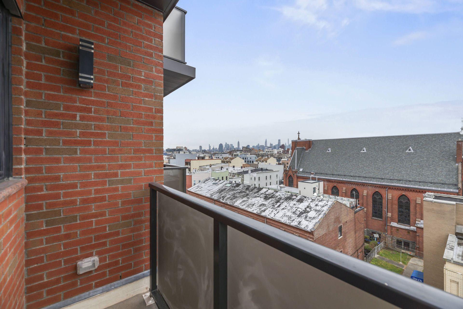 A balcony with a view of a city and a brick building.