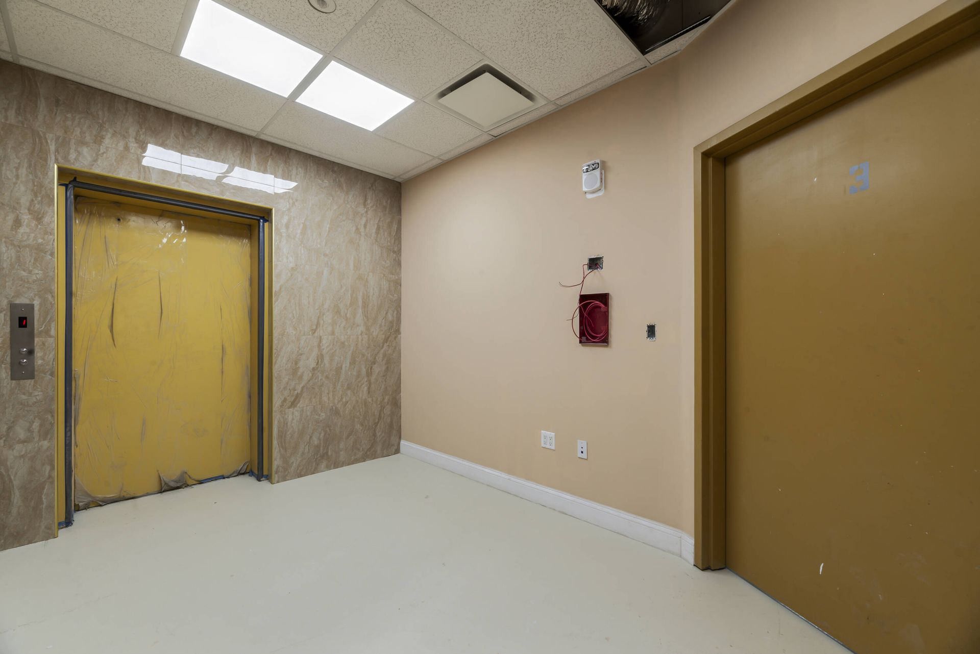 There are two elevators in the hallway of a building.