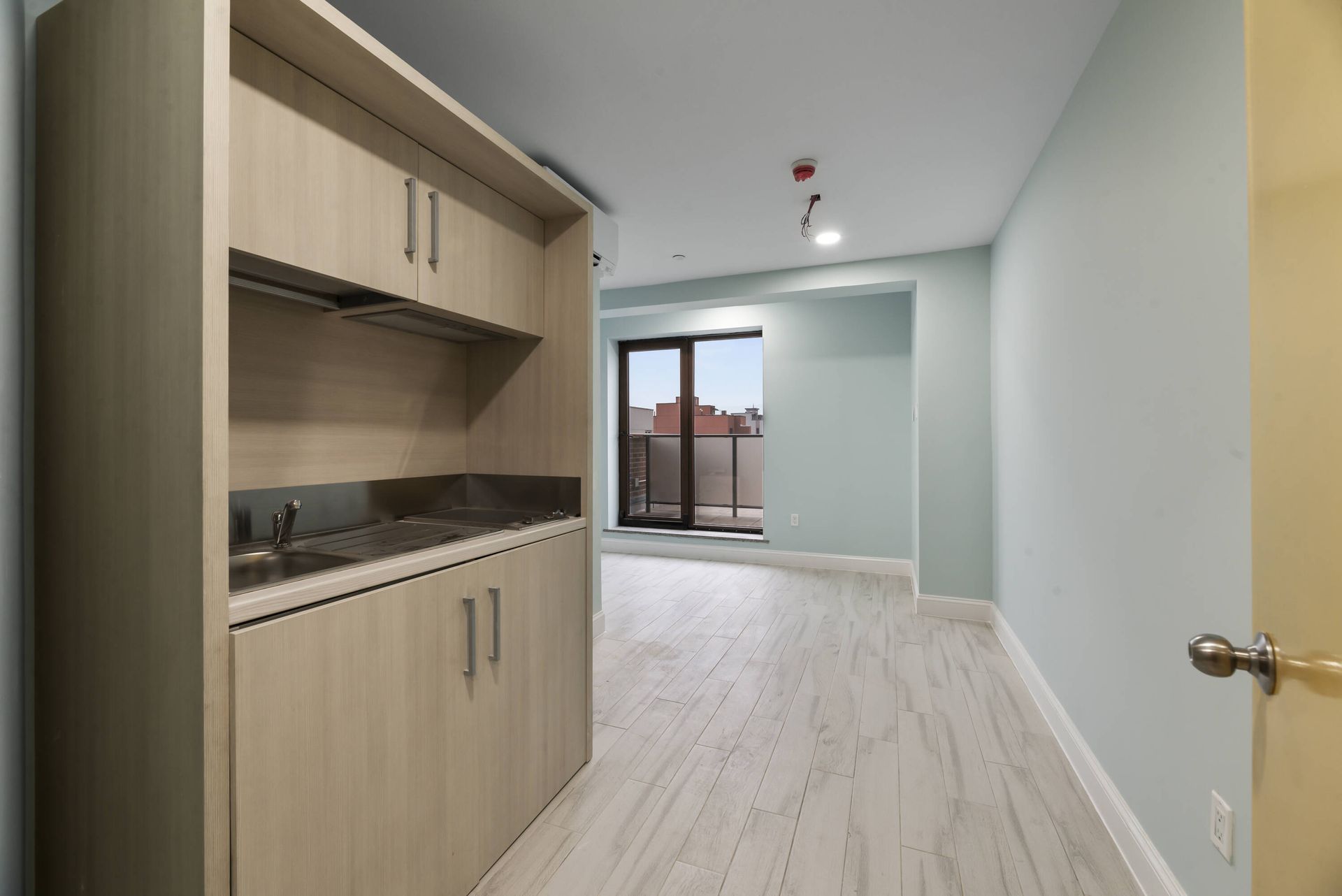 An empty room with a kitchen and a sliding glass door