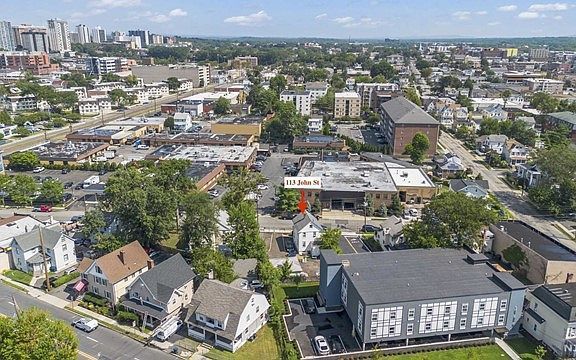 An aerial view of a city with a red arrow pointing to a building.