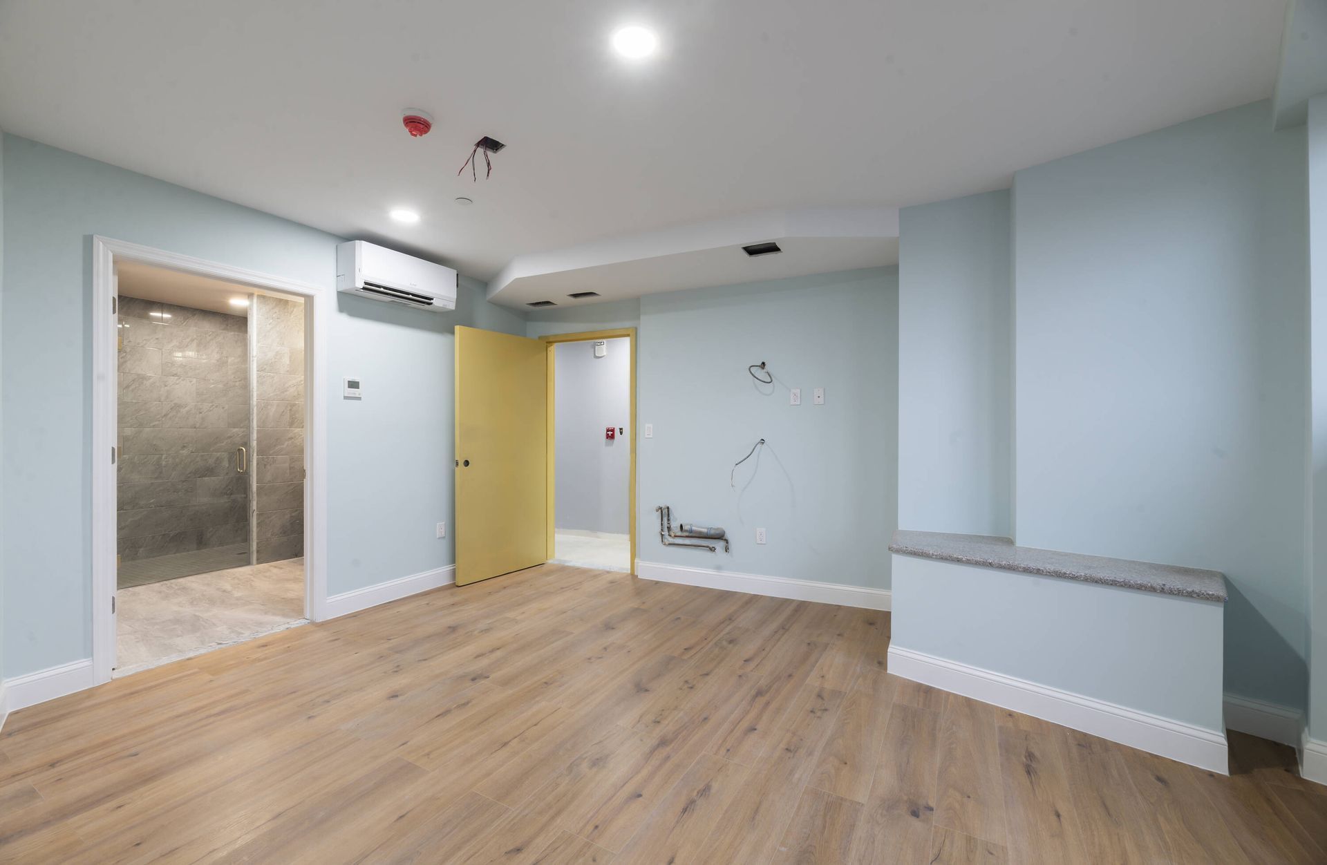 An empty room with hardwood floors and a yellow door.