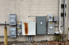 There are a lot of electrical boxes on the side of a building.