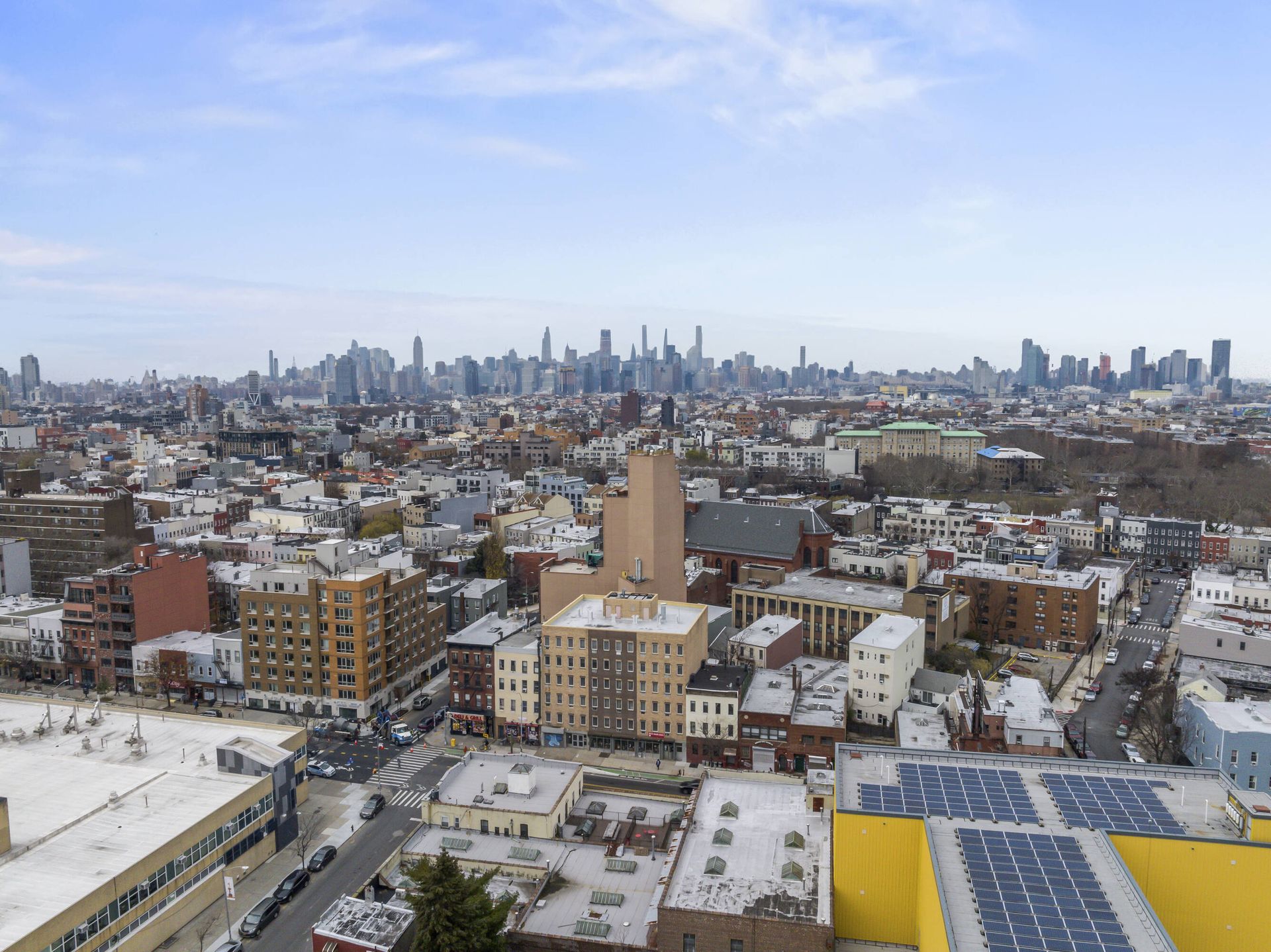 An aerial view of a city with a yellow building with solar panels on the roof