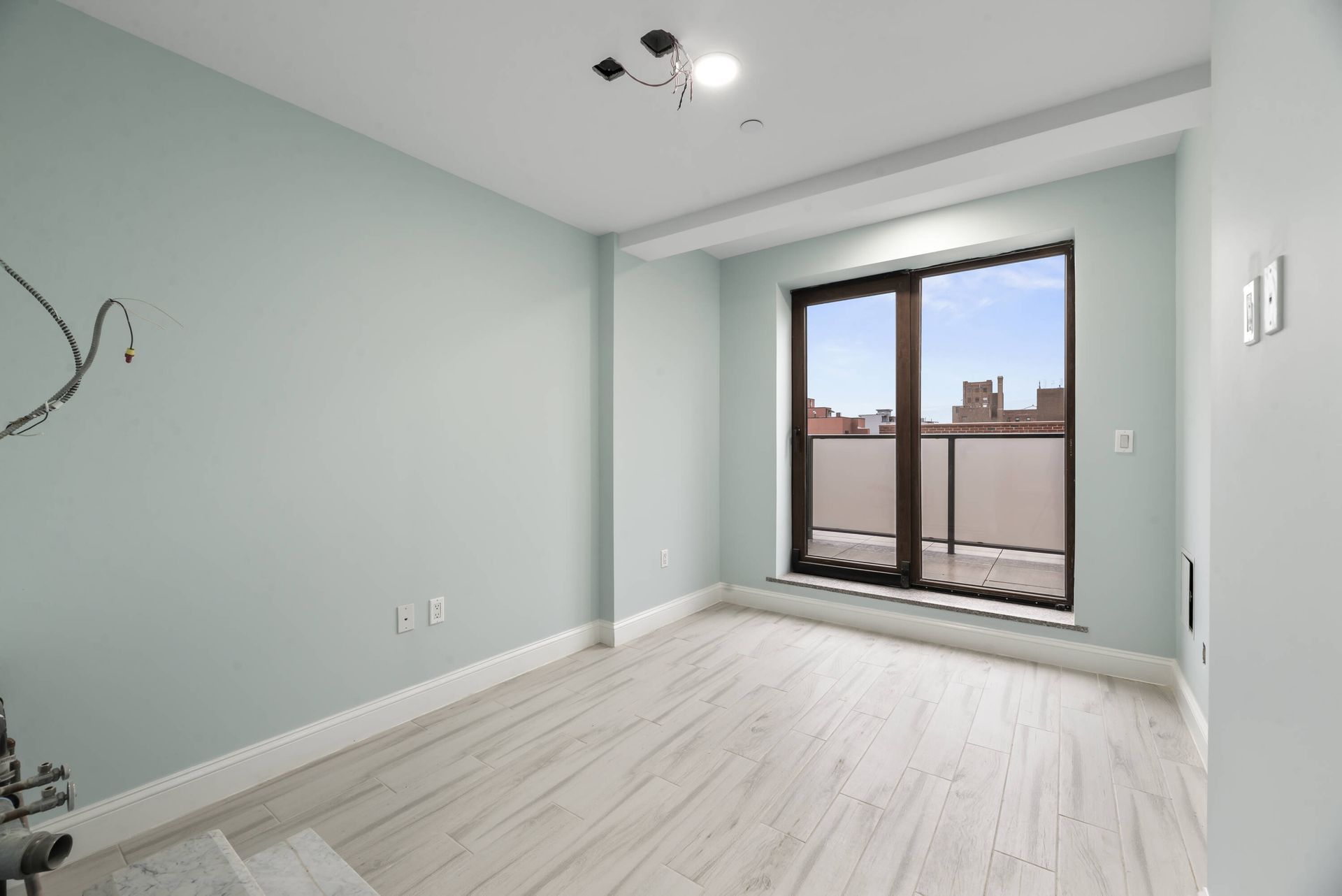 An empty room with a large window and a balcony.