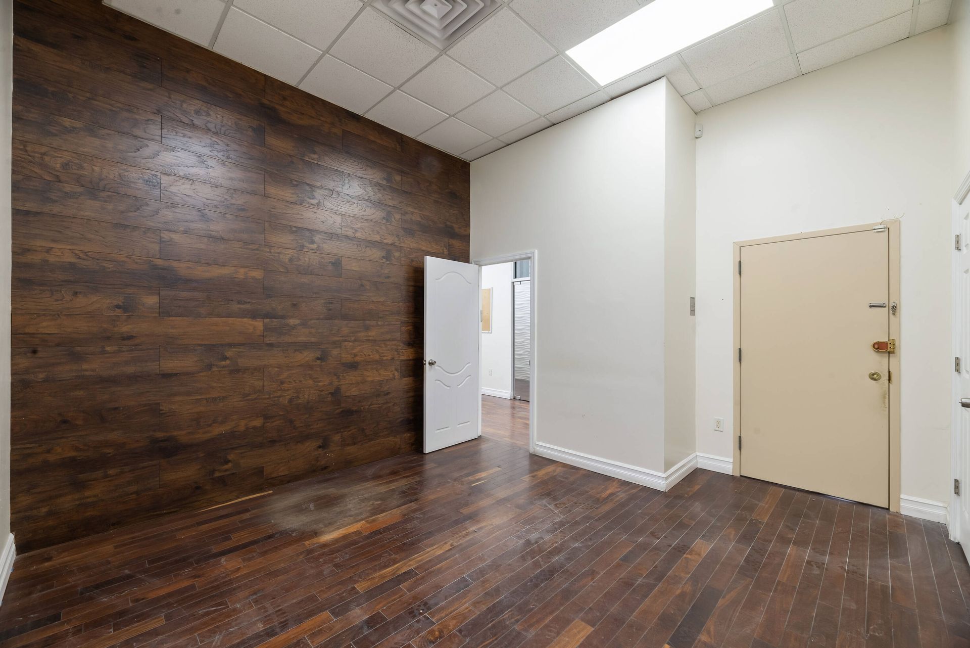 An empty room with hardwood floors and a wooden wall.