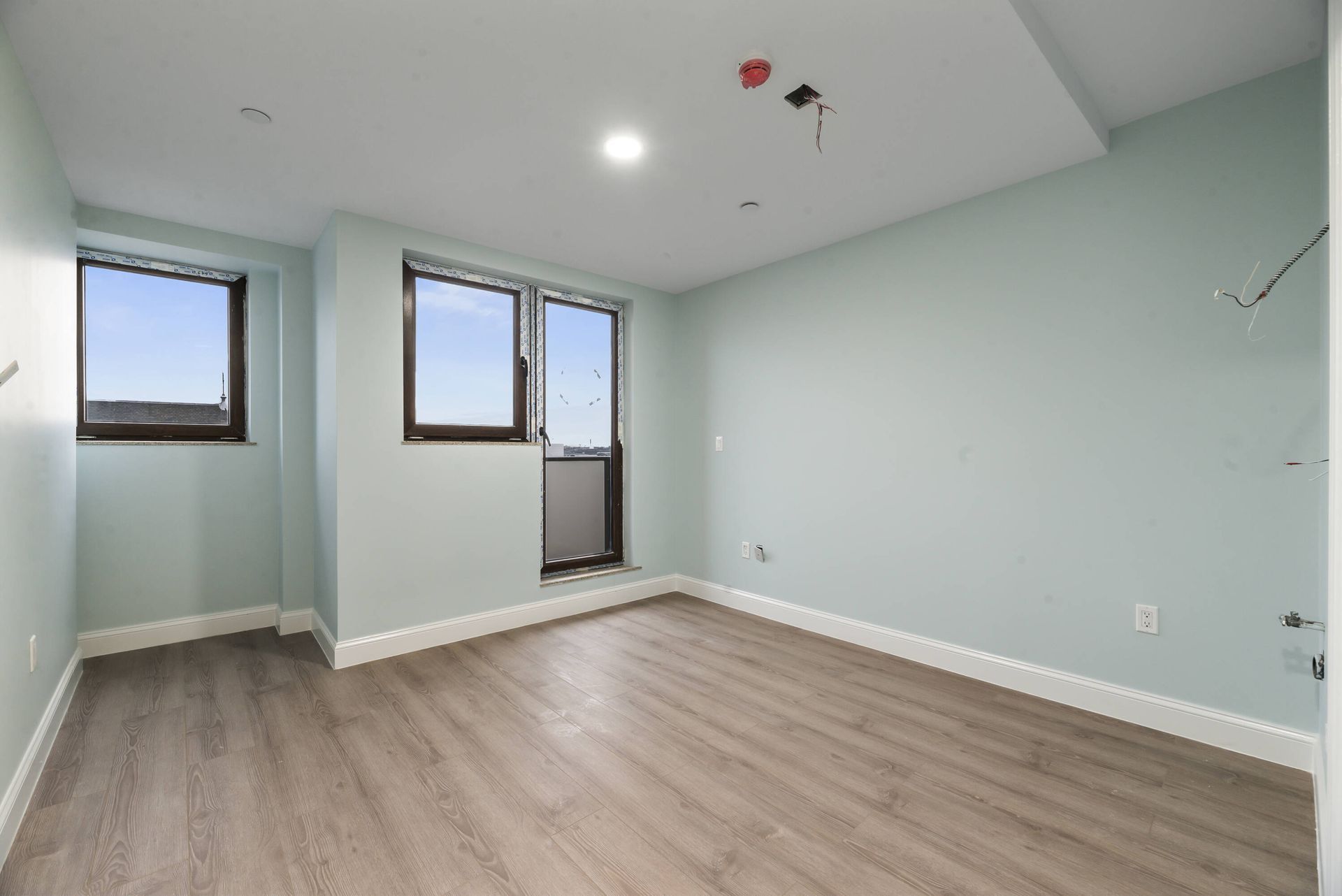 An empty room with hardwood floors and two windows