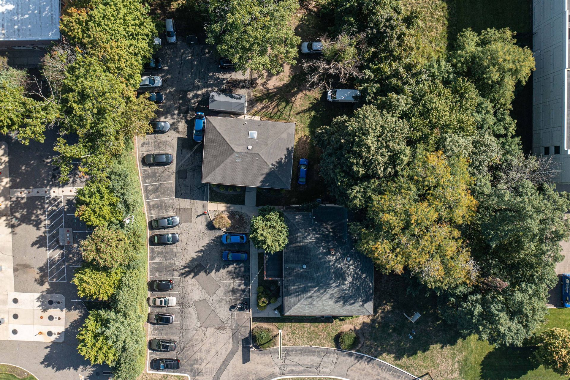 An aerial view of a house and a parking lot surrounded by trees.