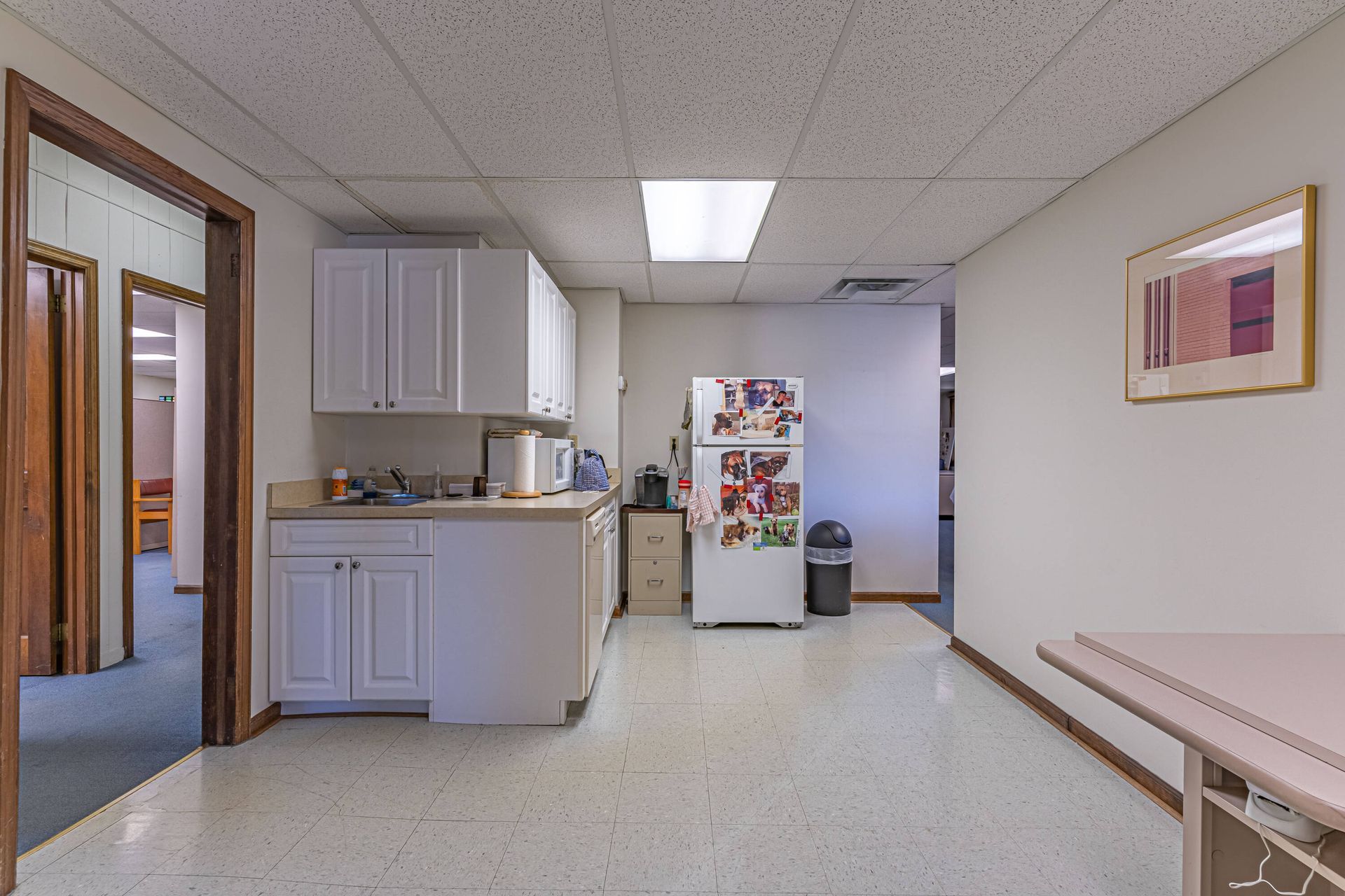 A kitchen with white cabinets and a refrigerator