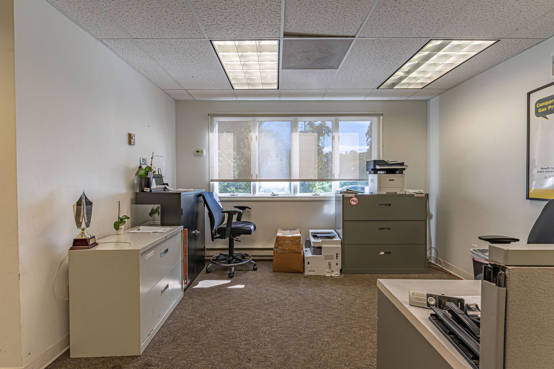 An office with a desk , chair , filing cabinets and a printer.