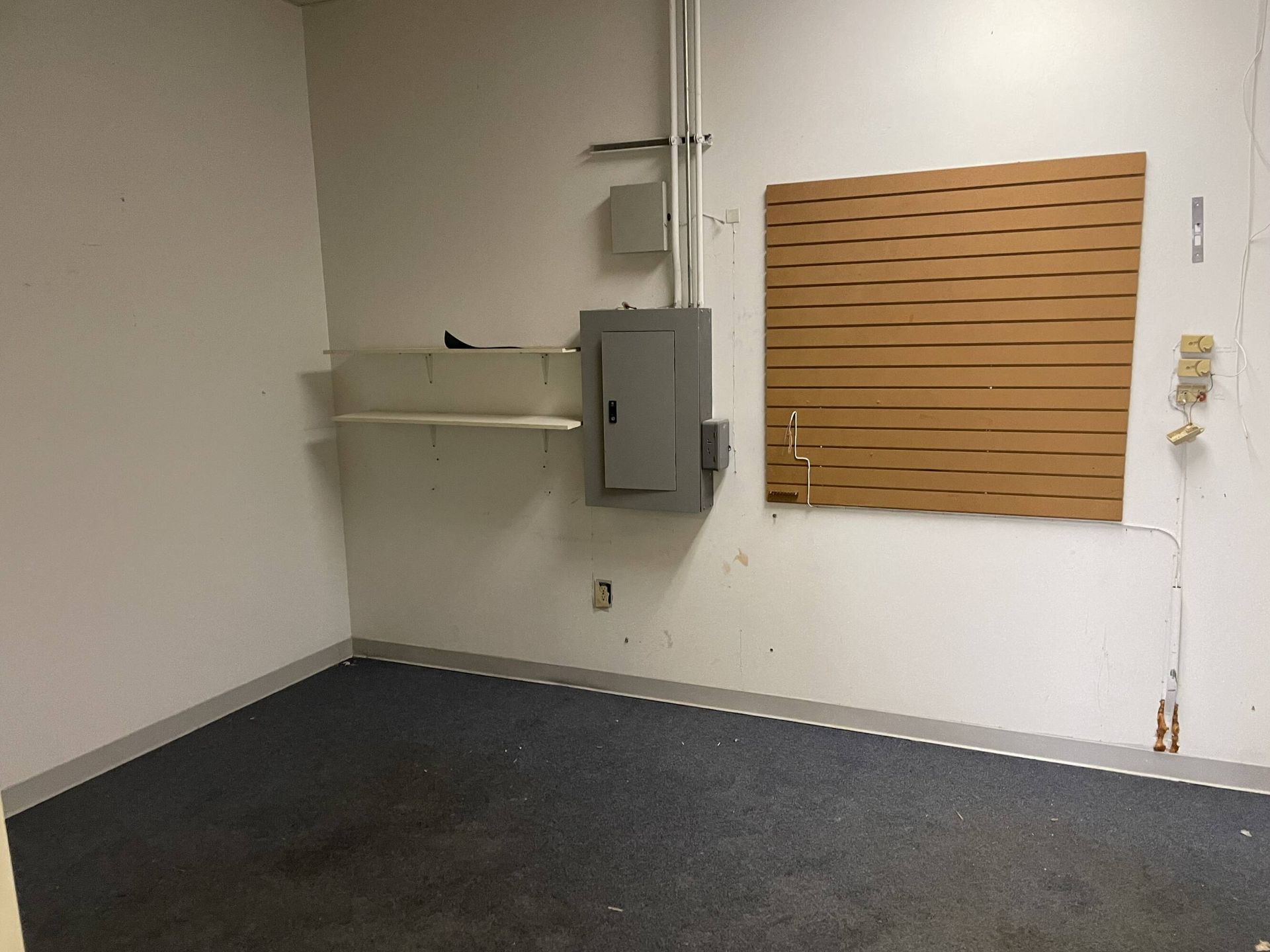 An empty room with a gray electrical box on the wall.
