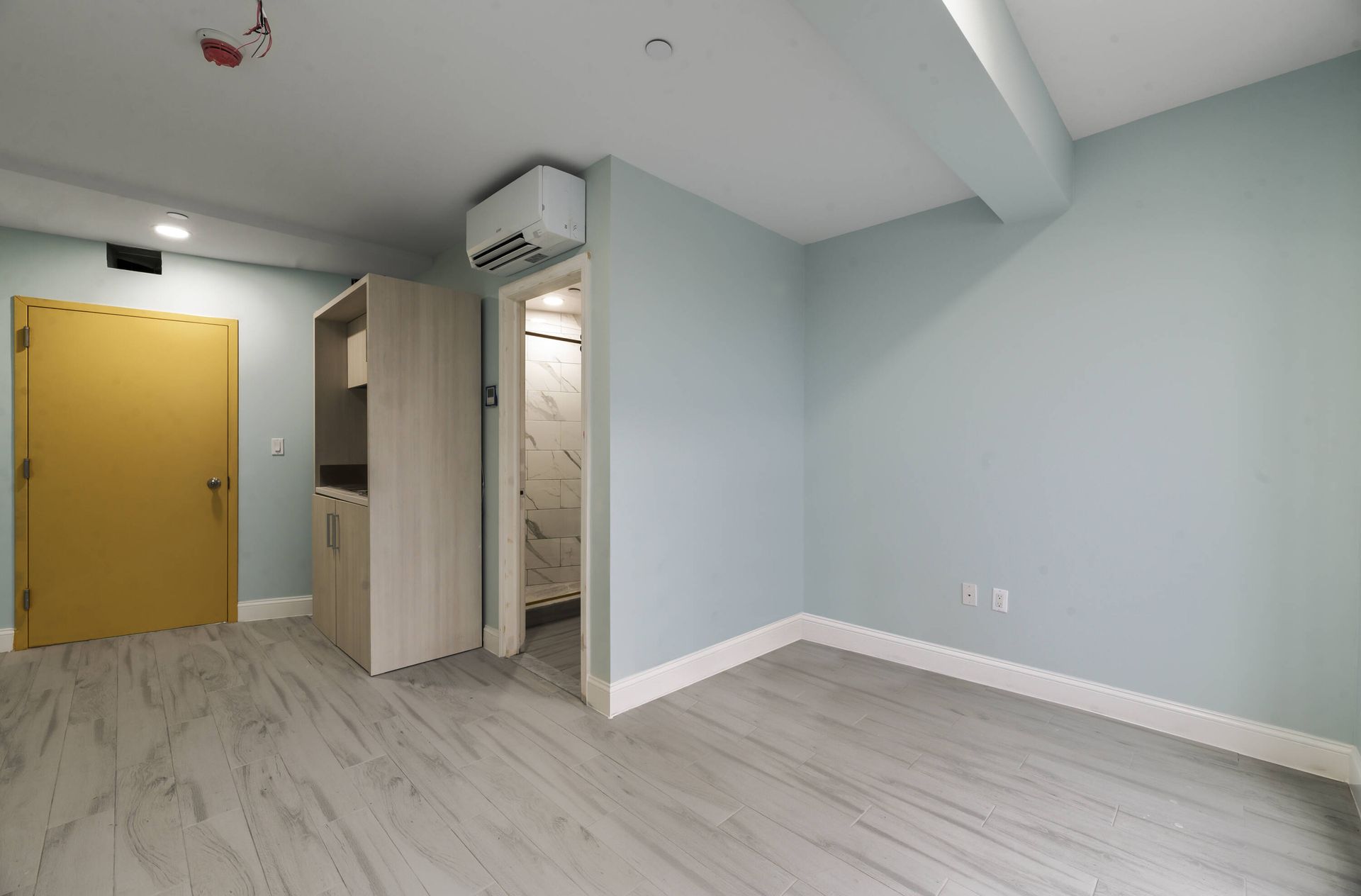 An empty room with blue walls and a yellow door.