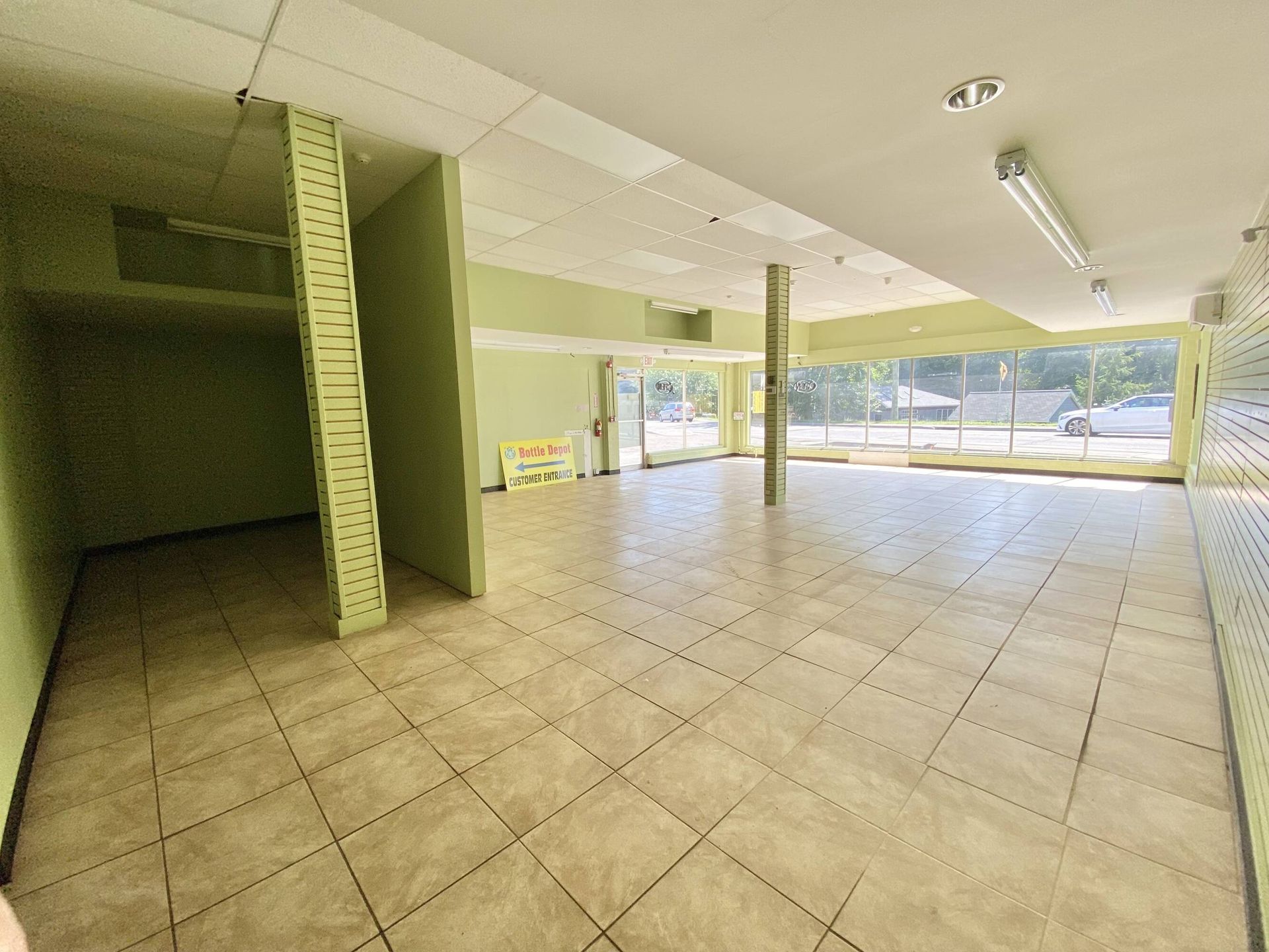 A large empty room with tile floors and green walls.
