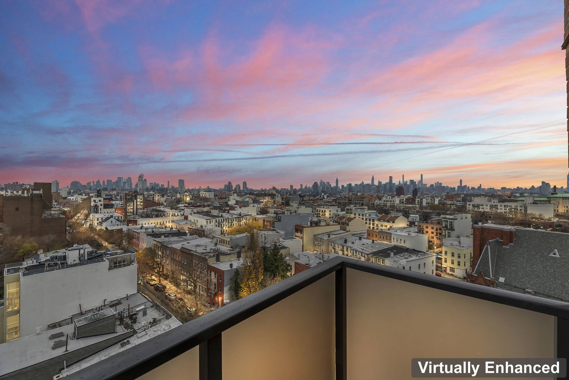 A balcony with a view of a city at sunset.