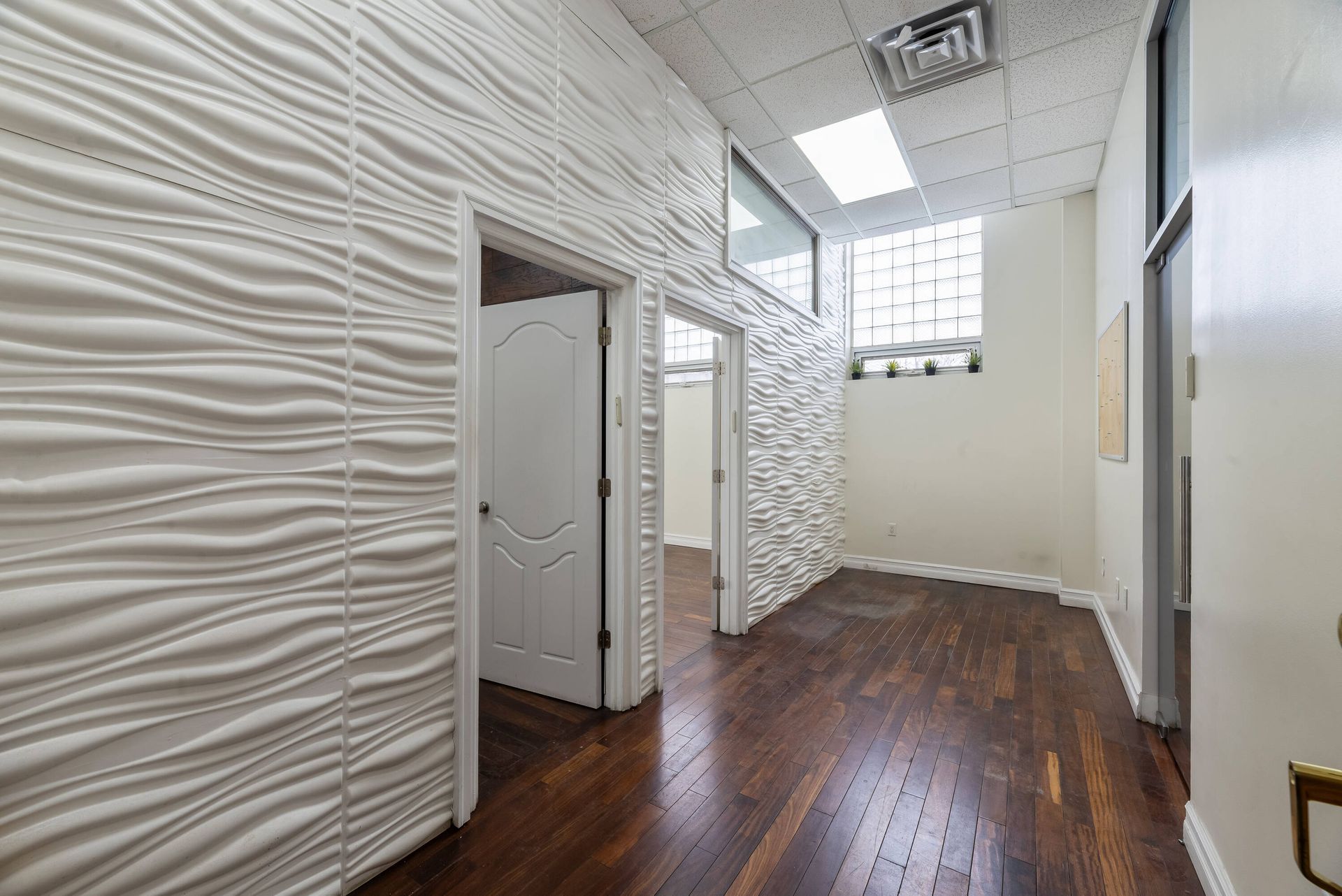An empty hallway with hardwood floors and white walls.