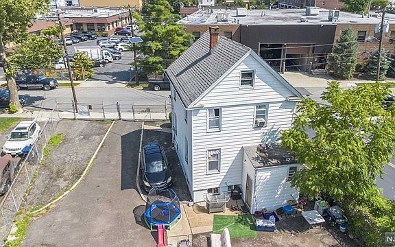 An aerial view of a white house with a car parked in front of it.