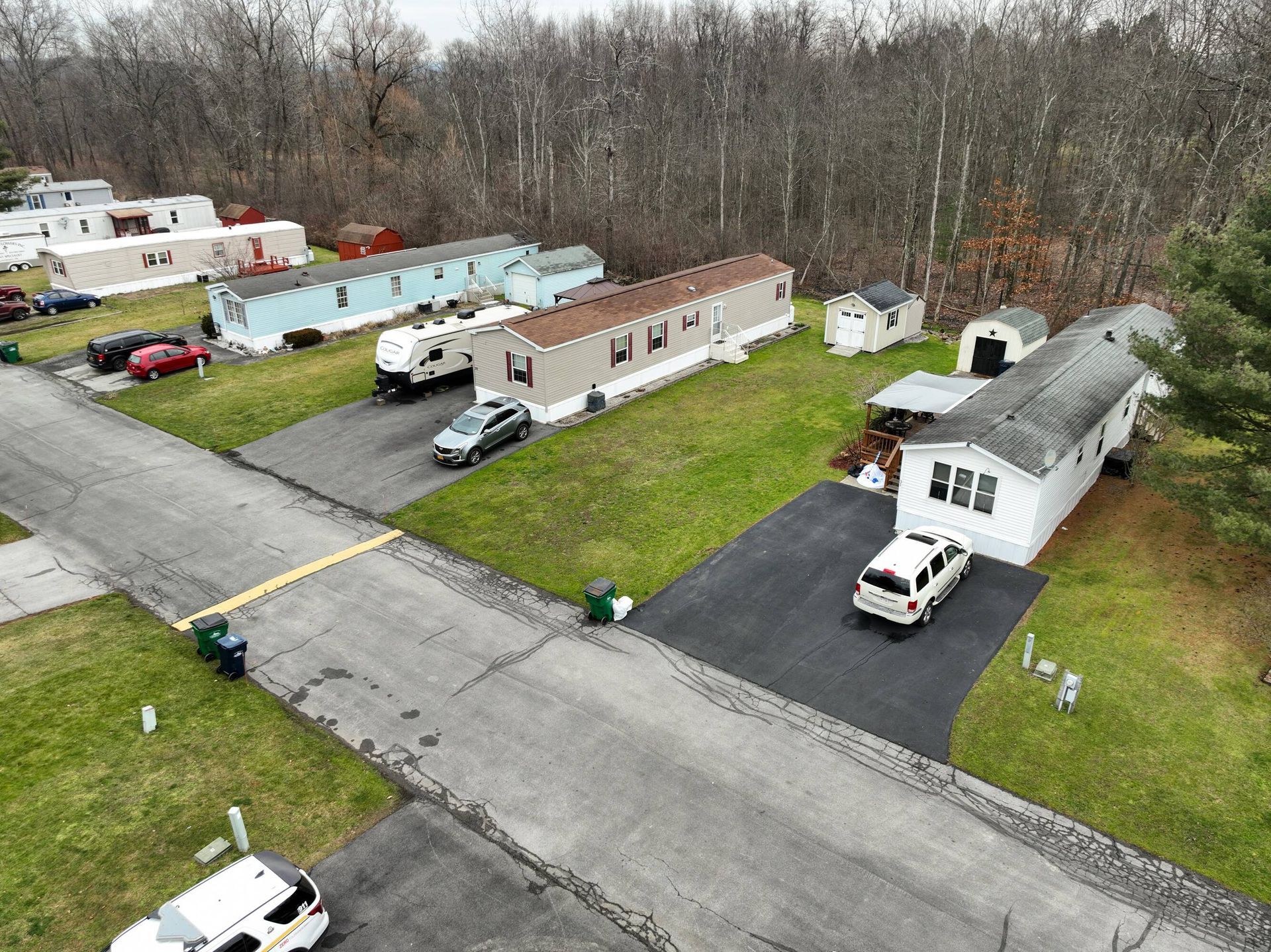 An aerial view of a mobile home park with a lot of houses and cars parked on the side of the road.