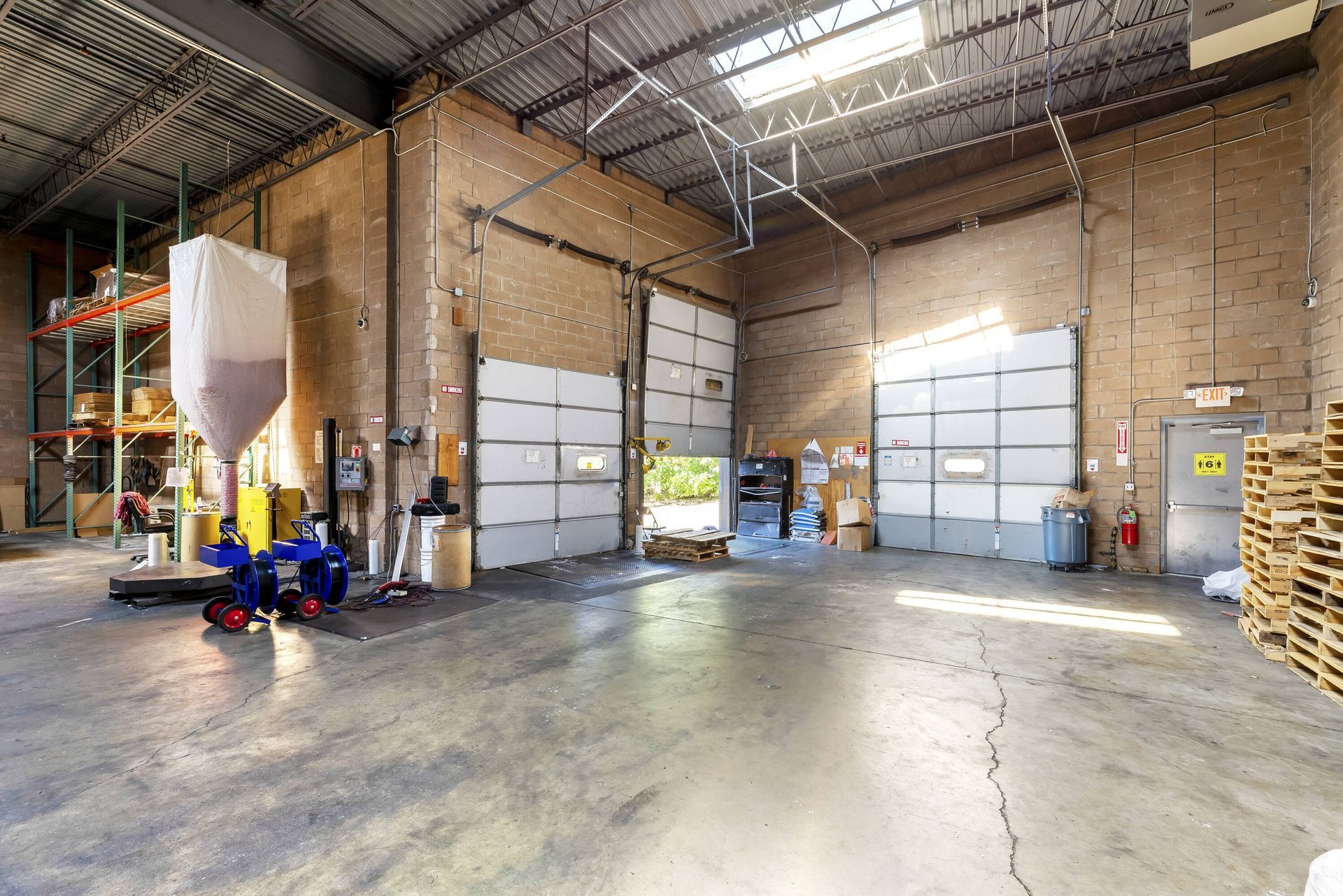 A large warehouse with lots of doors and pallets.