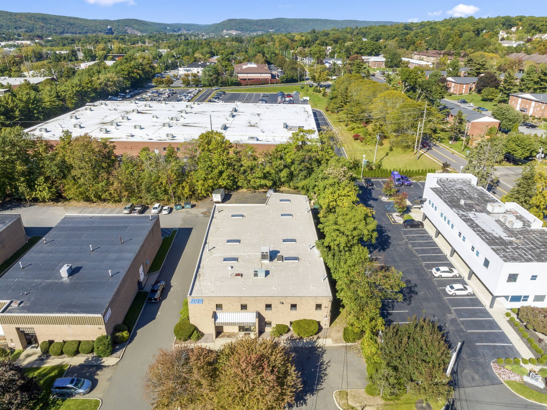 An aerial view of a large building in a residential area surrounded by trees.
