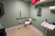 A bathroom with a toilet , sink and mirror.