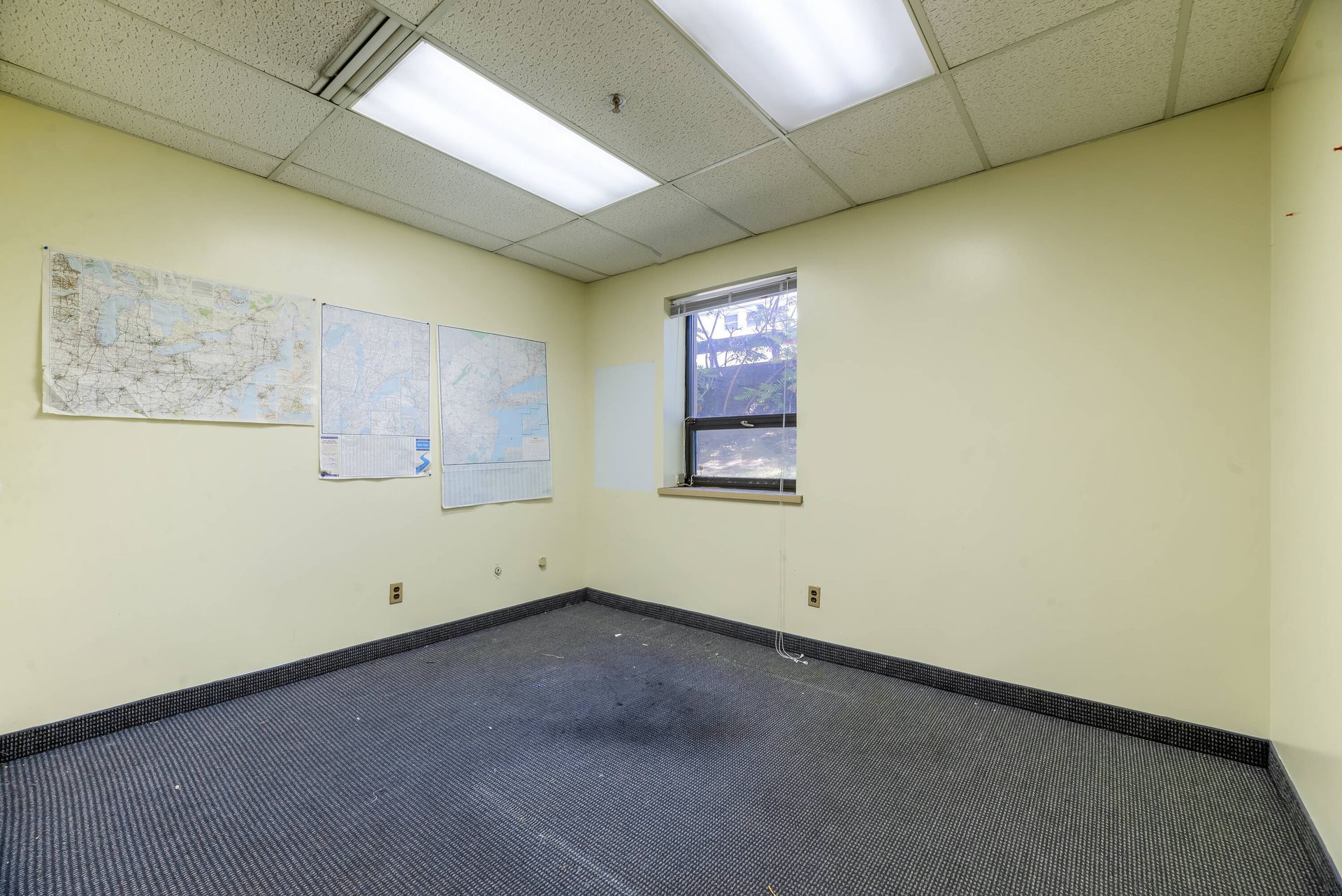 An empty room with a carpeted floor and a window.