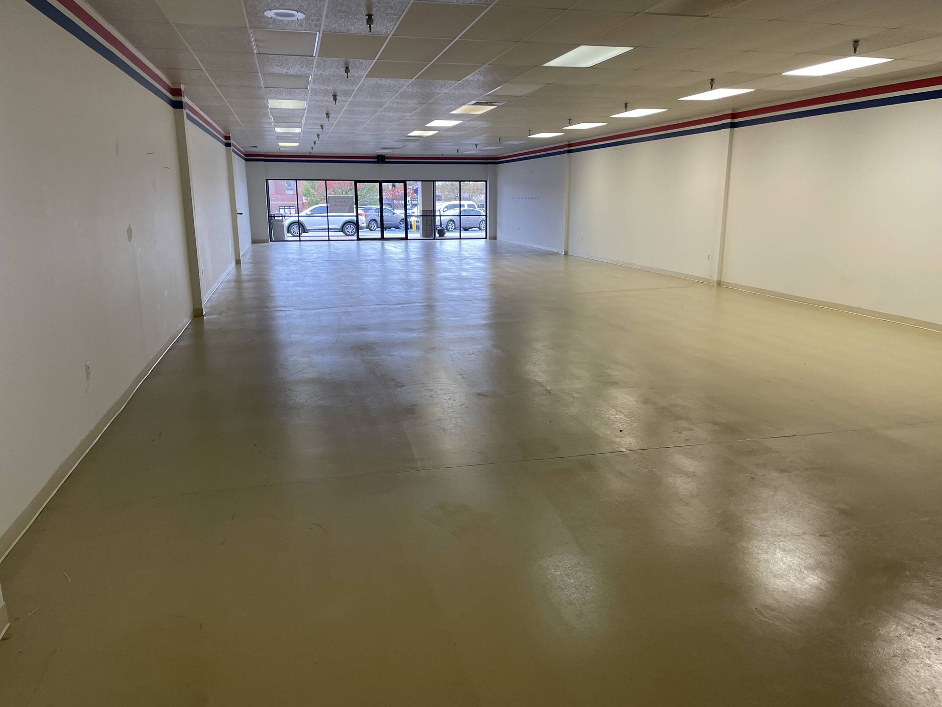 A large empty room with a concrete floor and white walls.
