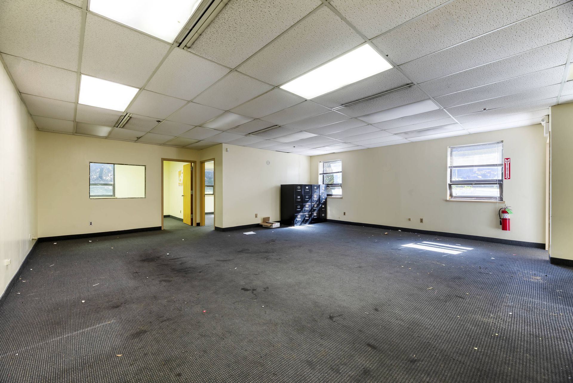 A large empty room with a fire extinguisher on the floor.
