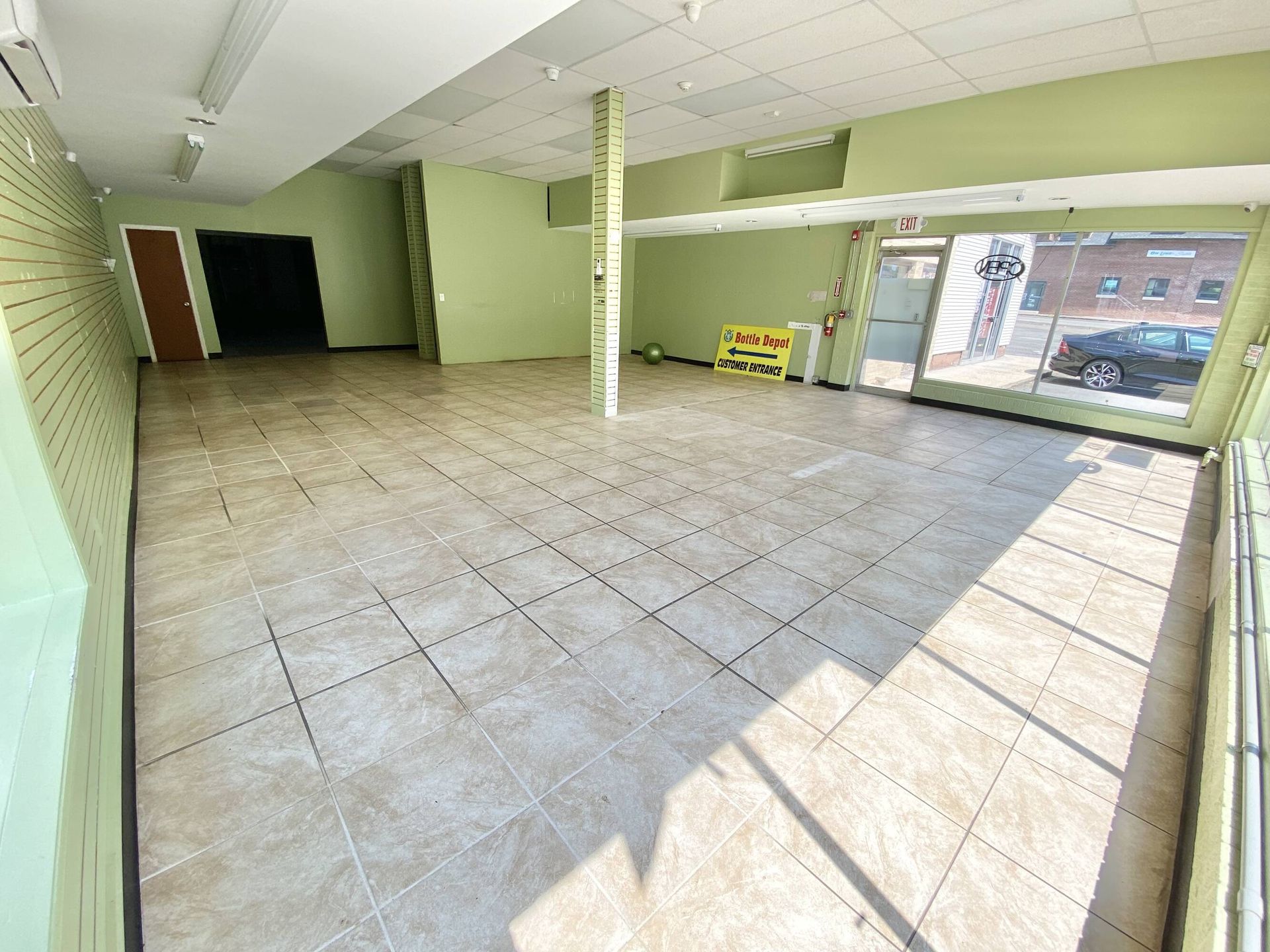 A large empty room with tile floors and green walls.