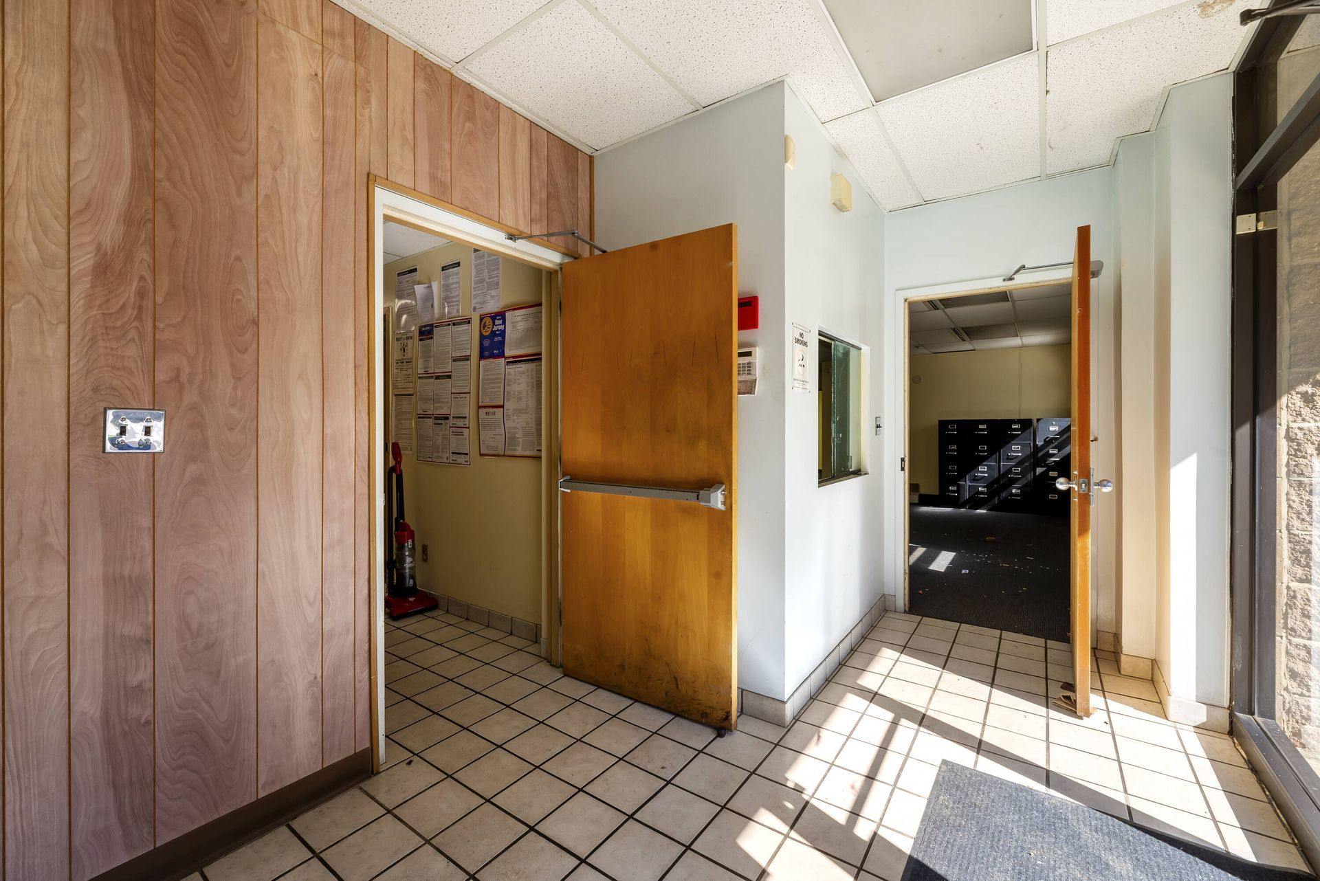 A hallway with a wooden door and a tiled floor