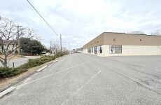 A large building is sitting on the side of a road next to a parking lot.