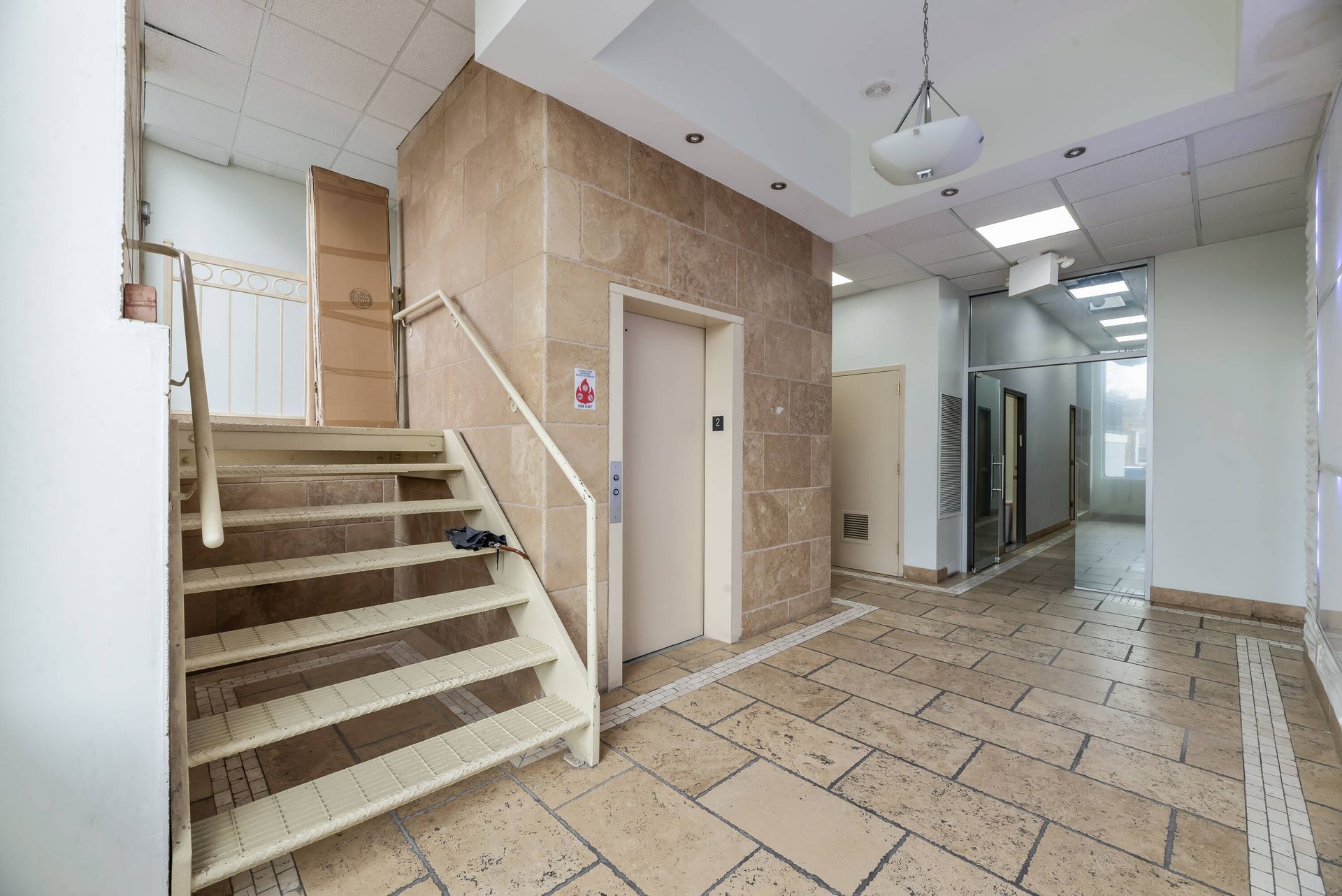 A hallway with stairs leading up to an elevator in a building.